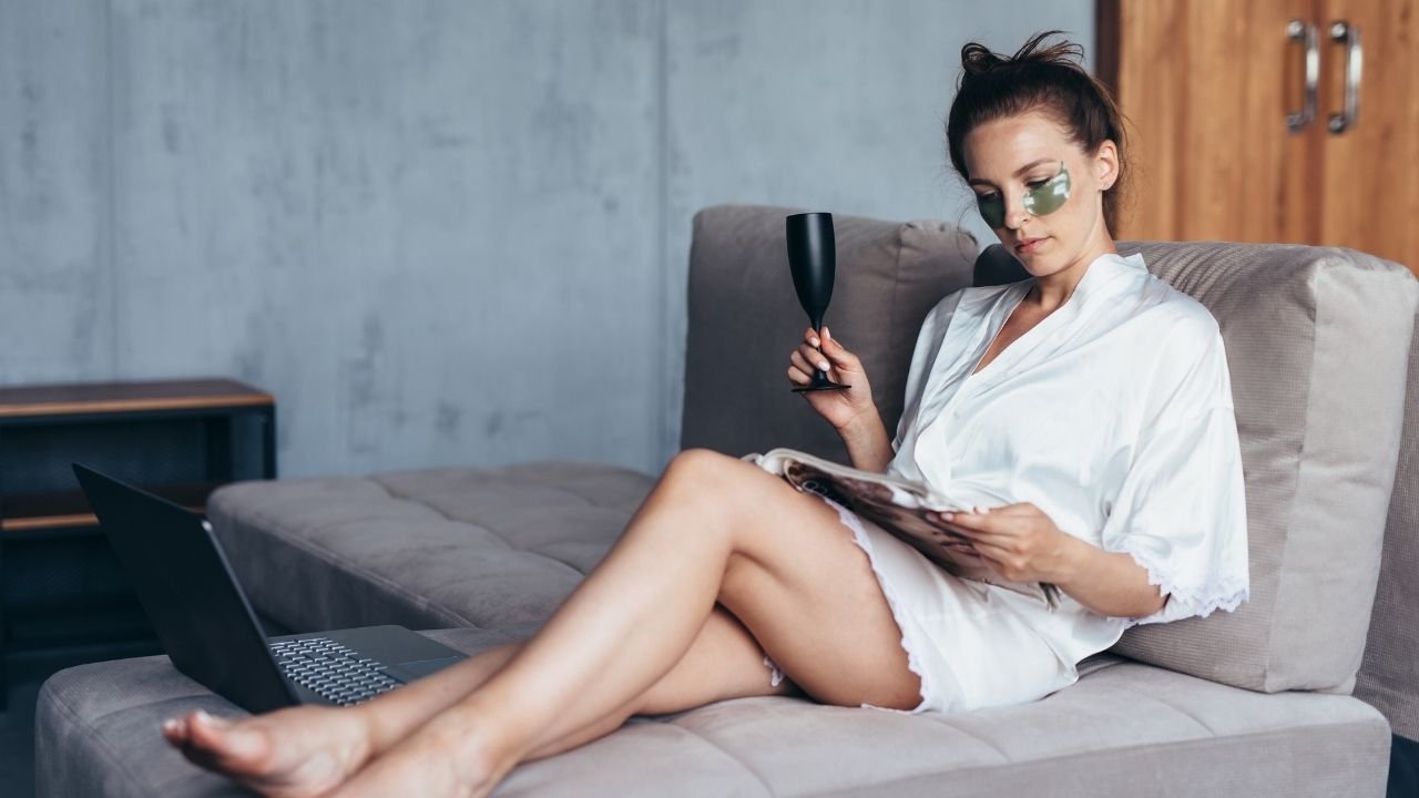 mulher com patch de olhos e robe branco lendo revista